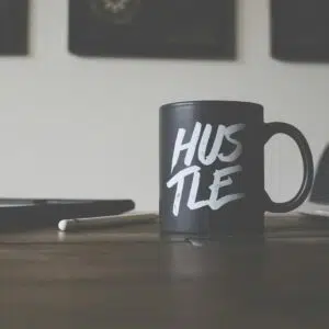 black and white Hustle-printed ceramic mug on table